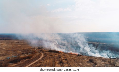 Forest And Field Fire. Dry Grass Burns, Natural Disaster. Aerial View. Extensive Burning Of Grass And Shrubs, All Around Is Obscured By Haze.