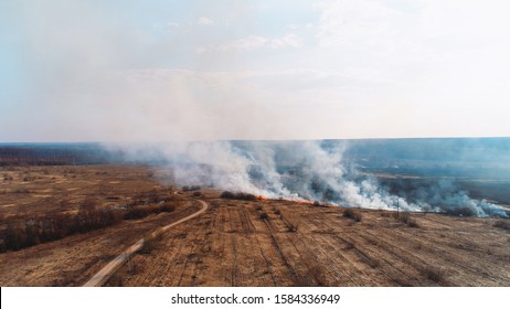 Forest And Field Fire. Dry Grass Burns, Natural Disaster. Aerial View. Extensive Burning Of Grass And Shrubs, All Around Is Obscured By Haze.