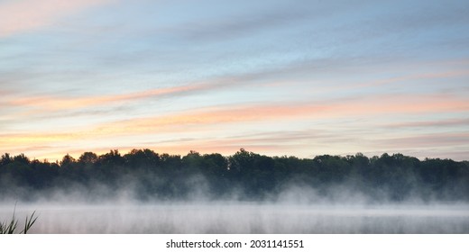 Forest Lake (river) In A Fog At Sunrise. Symmetry Reflections On The Water, Natural Mirror. Clear Pink Sky. Picturesque Panoramic Scenery. Nature, Environmental Conservation, Summer Vacations