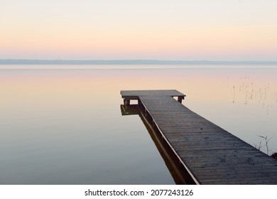 Forest lake (river) at sunrise. Wooden pier (boardwalk). Soft sunlight, mist, reflections on water. Idyllic autumn landscape. Pure nature, ecotourism, hiking, exploring