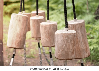 A forest obstacle course consisting of wooden logs suspended by ropes, ideal for adventure and climbing. - Powered by Shutterstock