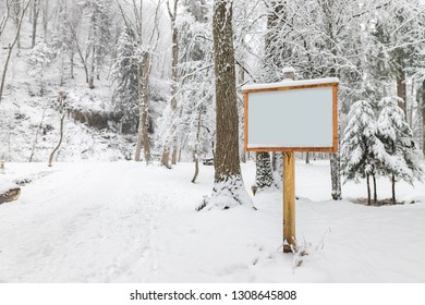 Forest / Park In Winter Snow Covered Nature With Blank Wooden Sign