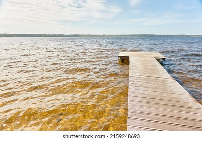 Forest river (lake) on a sunny day. Wooden pier. Clea sky, reflections in a crystal clear water. Idyllic landscape, rural scene. Nature, ecology, ecotourism, hiking, ecological resort, local tourism
