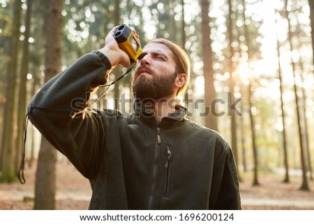 Forester determines the tree height with a laser rangefinder in the forest