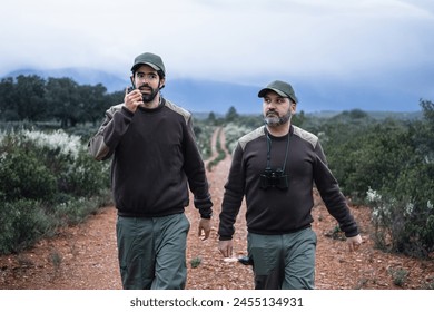 Forester man talking on walkie talkie radio , monitoring national park and environmental protection at dusk - Powered by Shutterstock