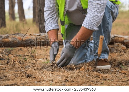 Forester with spade checking soil in forest, closeup