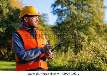 Forestry engineer. Control inspector checks logging. Ecologist volunteer man in workwear. Male eco technic with clipboard checking trees.
