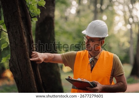 Forestry engineer examining tree bark for signs of disease or insect infestation, holding clipboard and wearing safety helmet