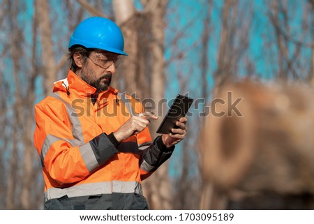 Forestry technician using digital tablet computer in forest for logging data collecting during deforestation