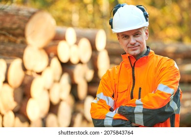 Forestry worker in protective workwear in front of wood lumber cut tree - Powered by Shutterstock