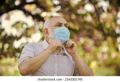 Forewarned means protected. life during coronavirus lockdown. fear of illness. strategy in battling virus. prohibition on visiting public places. senior man in medical mask. blossom tree in park - Shutterstock ID 2143301745