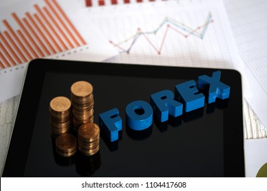 FOREX text and stack of coin with tablet computer and financial graph chart on paper, business planning vision and finance analysis concept idea.