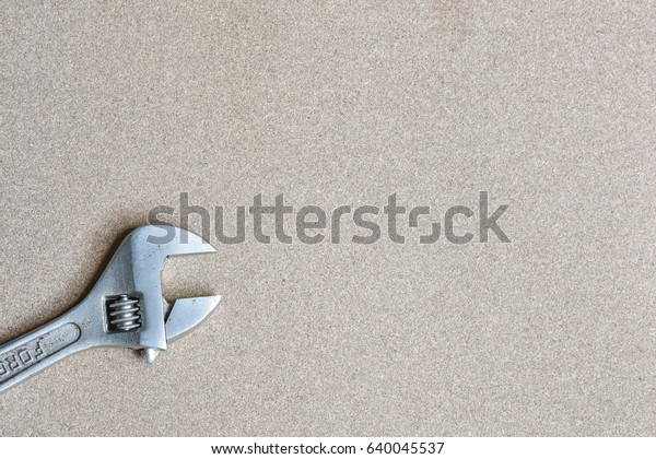 A forge adjustable wrench spanner\
tools lying on wood background with a copy space for\
text