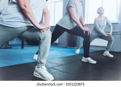 Forget About Your Joint Pain. Scale Up Shot Of A Group Of Senior Ladies Standing In A Row And Doing Lunging Exercises While All Three Training In A Gym.