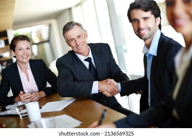 Forging Business Relationships. A Group Of Professional Businesspeople In A Meeting And Concluding A Deal With A Handshake.