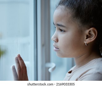 A Forgotten Child Should Be A Punishable Offence. Shot Of A Little Girl Starting Out Of The Window Looking Sad At Home.