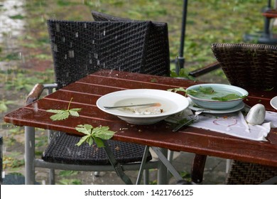 Forgotten Dishes On A Table In The Beer Garden During A Rain Shower