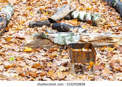 Forgotten Small Barbecue Grill With Trash On Meadow Covered By Fallen Leaves In City Park In Autumn