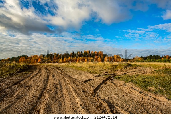 Fork of a country dirt\
road passing through a field. Traces from the wheels of cars are\
clearly visible. The main road goes to the left, the track turns to\
the right. 