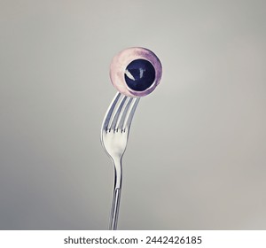 Fork, eyeball and eyes as halloween concept on grey background and weird or crazy art or strange. Horror, odd and abstract of macabre eating in psychology, nightmare and object of discomfort for fear