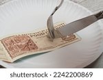 Fork and knife cutting a food coupon on a paper plate
