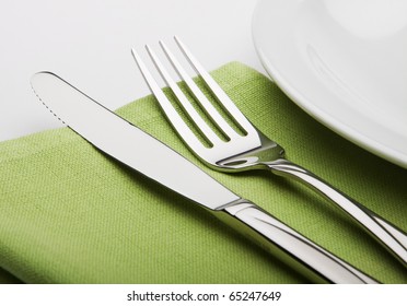 Fork And Knife On A Green Napkin With Plate.