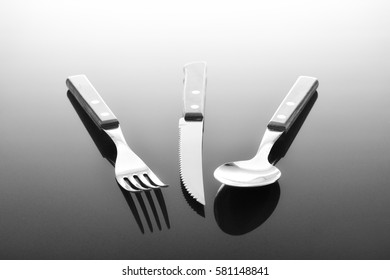 Fork, Knife And Spoon On Glossy Table Surface
