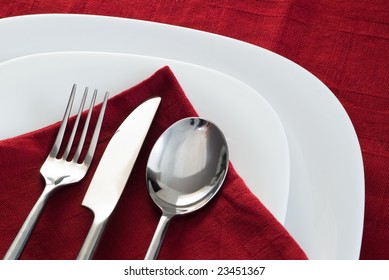 Fork Knife And Spoon On White Plate And Dark Red Napkin