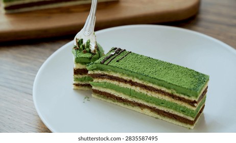 Fork lifting matcha cake bite presented in a detailed culinary, dessert, or fresh food setting.