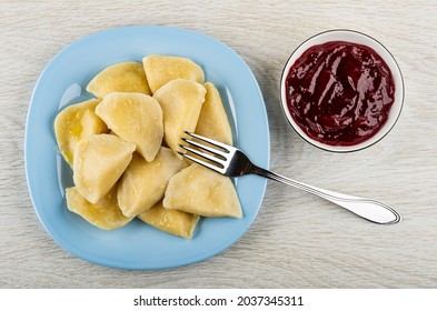 Fork In Light-blue Plate With Boiled Dumpling, Bowl With Cherry Jam On Wooden Table. Top View