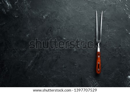 Fork for meat on a black background. Top view. Free space for your text.
