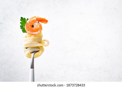 Fork With Pasta And Shrimp On White Background, Copy Space. Fettuccine Pasta With Cream Alfredo Sauce And Shrimp On Fork Close Up.