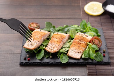 Fork Pricking Salmon Fillets On Slate Dish On Wooden Table Background.