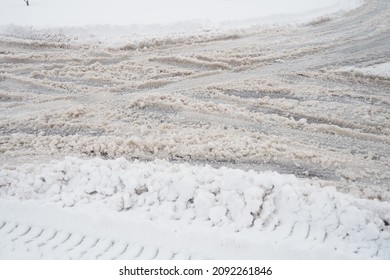 A fork or siding from a roundabout. Snowdrifts on the side of the road. Bad weather and traffic. Snow on the asphalt. Difficult driving conditions. Winter slush on the auto path