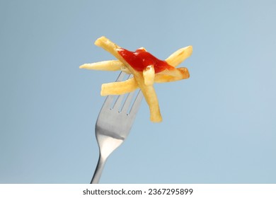 Fork with tasty french fries against light blue background, closeup - Powered by Shutterstock