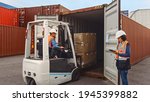 Forklift Driver Loading a Shipping Cargo Container with a Full Pallet with Boxes in Logistics Port Terminal. Latin Female Industrial Supervisor and Safety Inspector with Tablet Managing the Process.