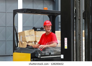 Forklift driver with red helmet  in distribution warehouse