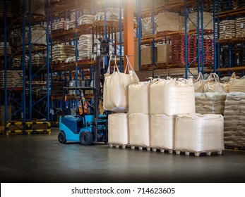 Forklift is handling jumbo bags in large warehouse.