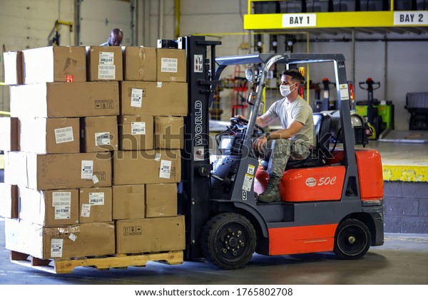 Forklift / lift truck driver operating forklift /\
lift truck and transporting goods / cargo / logistic from at Amazon\
warehouse or ship dock yard in crona virus in Berlin, Germany on\
6th June 2020