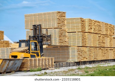 Forklift loading lumber wood boards in stack, finished product warehouse ready for transportation. Sawn boards stack in row. Worker on loader stack in row wooden boards at sawmill - Powered by Shutterstock