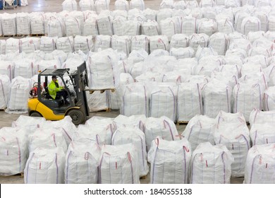 Forklift operator lifting large bag of recycled plastic pellets in warehouse
