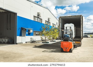 Forklift Operator Preparing to Load Goods into Open Truck at Warehouse