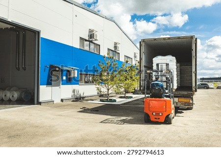 Forklift Operator Preparing to Load Goods into Open Truck at Warehouse