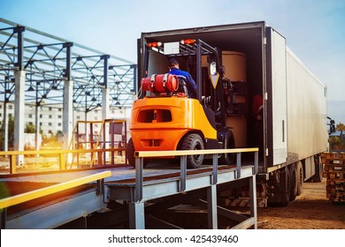 Forklift Is Putting Cargo From Warehouse To Truck Outdoors