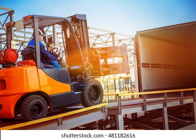 Forklift is putting cargo from warehouse to truck outdoors at sunny sky background. - Powered by Shutterstock