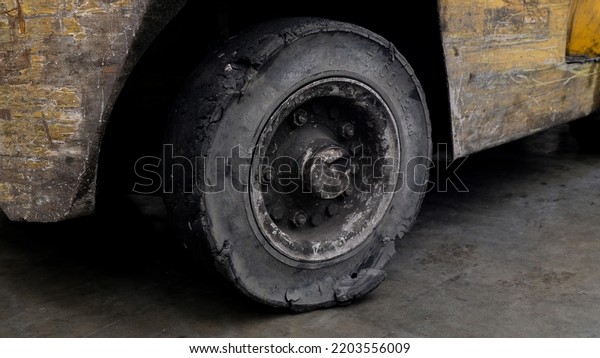 Forklift tires in the factory With torn tire\
condition and not safe to use. Broken car on the road with damaged\
tire and disk. closeup damaged 18 wheeler semi truck burst tires by\
highway street.
