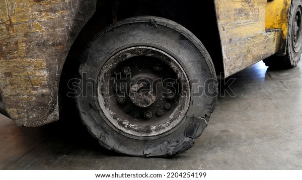 Forklift tires in the factory With torn tire\
condition and not safe to use. Broken car on the road with damaged\
tire and disk. closeup damaged 18 wheeler semi truck burst tires by\
highway street.