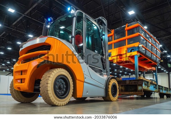 Forklift truck during work. She is engaged in\
loading cargo onto the platform. Concept - warehouse special\
equipment. Small car with stackers function. Forklift truck inside\
warehouse.