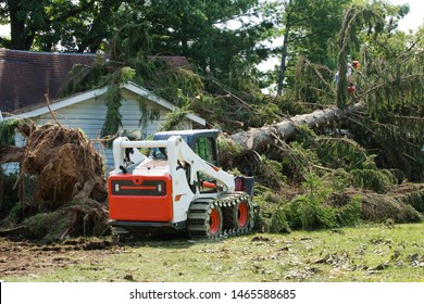 Forklift Truck Grabs Wood In A Wood. Skid Steer Loader.Home Insurance. Insurance Storm.Storm Damage.Roof Damage From Tree That Fell Over During Hurricane Storm.Lumberjack Cutting Tree. Tree Down.