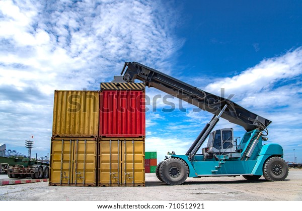Forklift truck lifting cargo container on\
shiping yard ,stack of containers without labels,import/export\
logistic\
transportation,